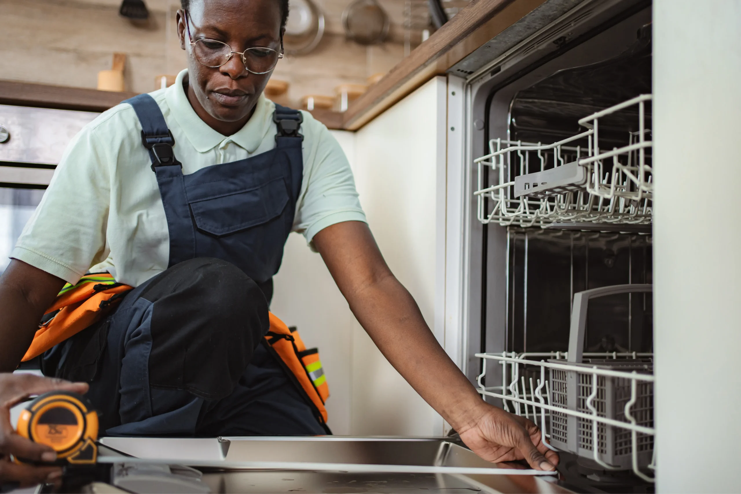 technician taking measurements for dishwasher installation in kitchen photo 1